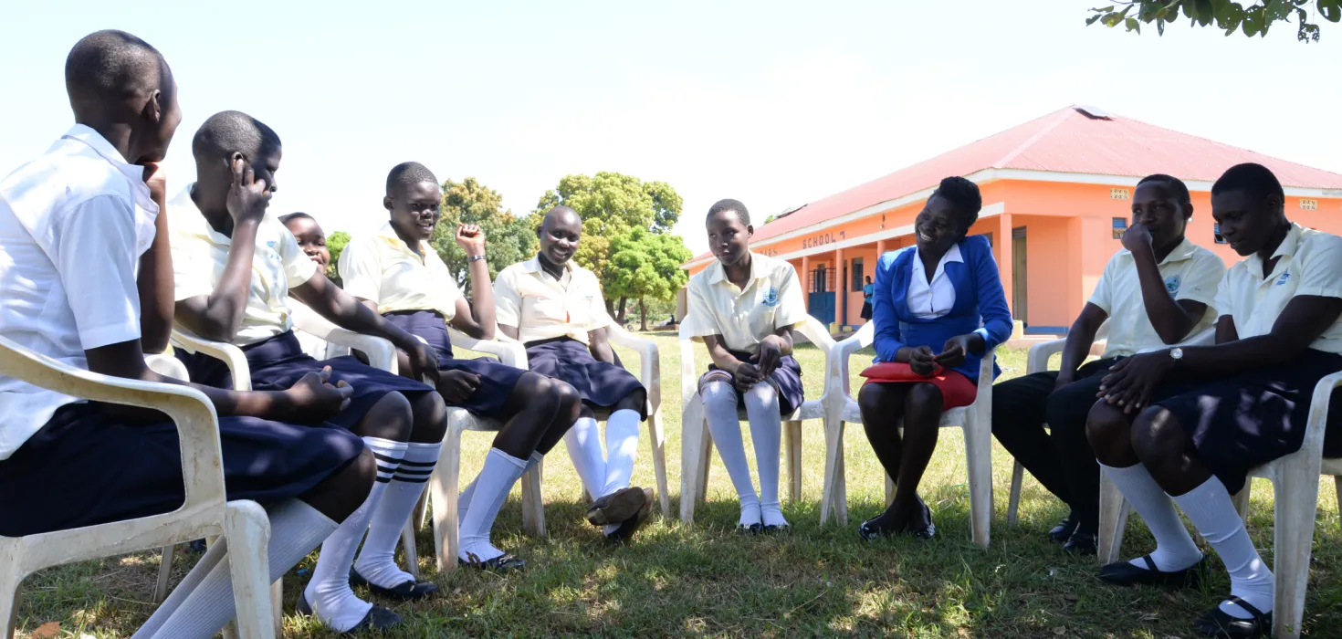 Lehrerin Elizabeth aus Uganda im Kreis mit ihren Schülerinnen und Schülern 