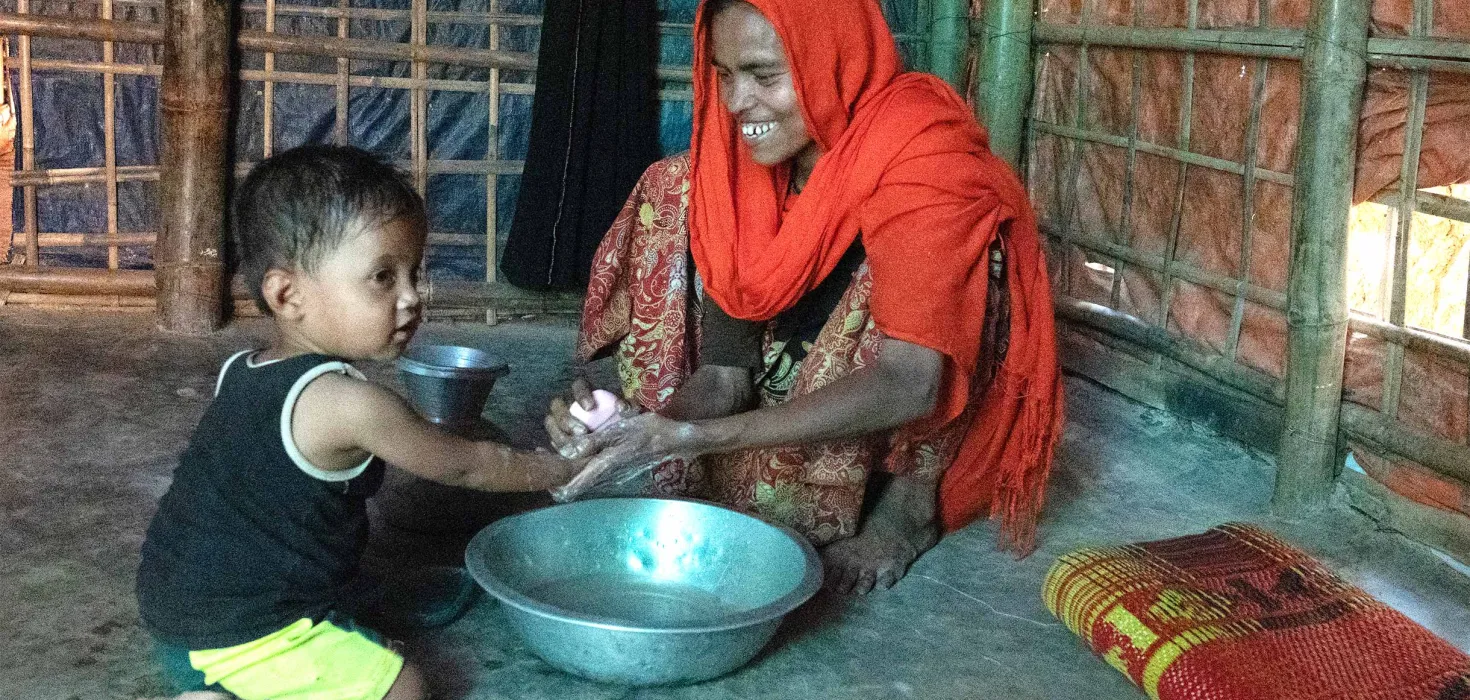 Mutter im Flüchtlingscamp in Bangladesch wäscht ihrer Tochter die Hände