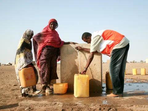 World Vision Mitarbeiter hilft am Brunnen