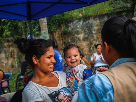 Ein kleines Kind in Venezuela lacht einem World Vision-Mitarbeiter bei einem Besuch im Rahmen der Erdbeben-Nothilfe zu.
