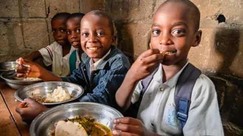 Drei Kinder aus Afrika, die eine Schulmahlzeit essen