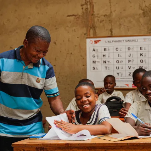 Lehrer mit Schülerinnen und Schülern in einem Klassenraum in DRC