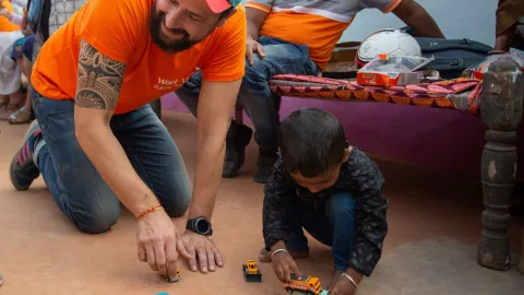 Paul spielt mit seinem Patenkind in Indien mit Autos